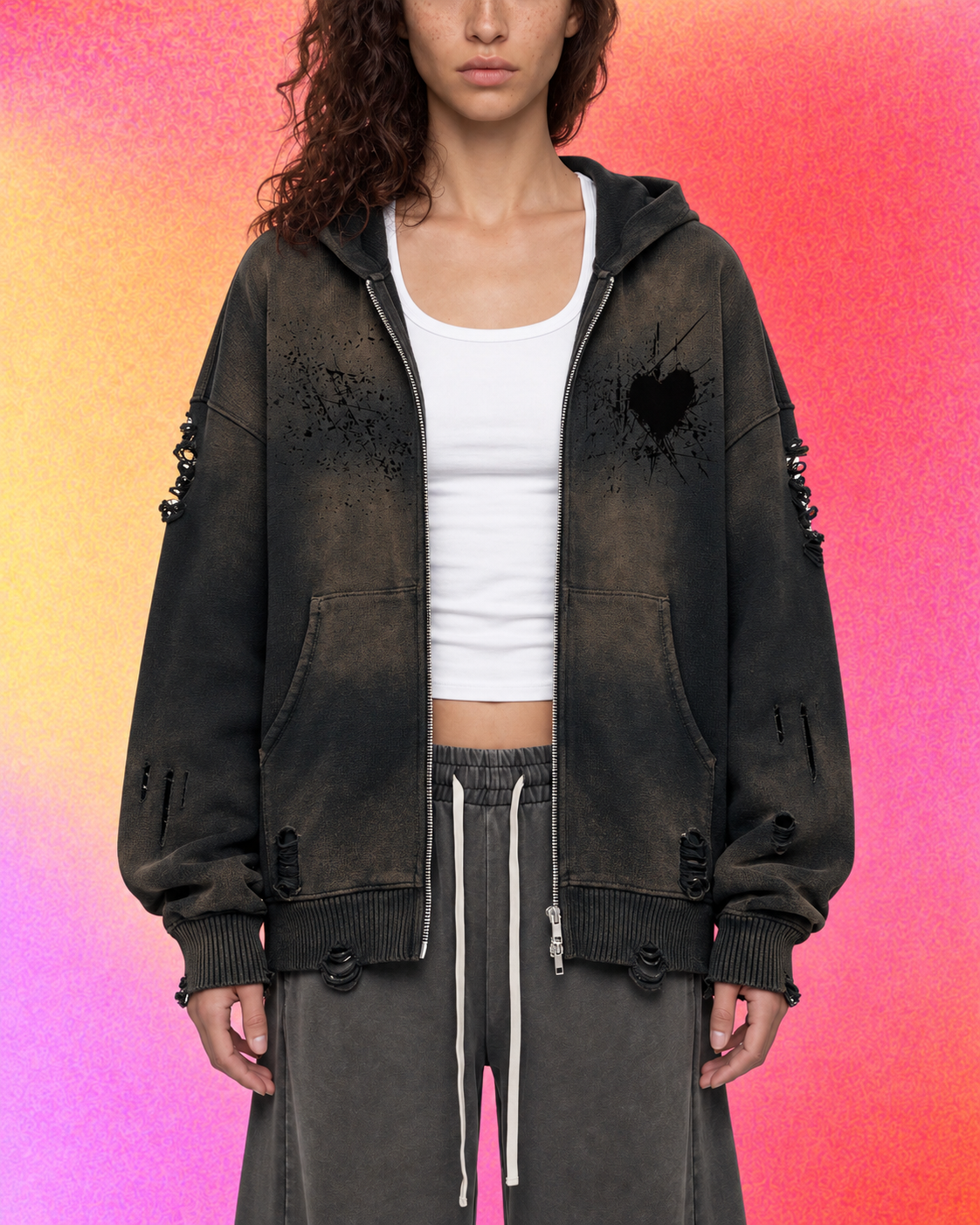 Model wearing the black heart hoodie with hands in pockets against a plain backdrop.