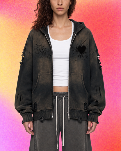 Model wearing the black heart hoodie with hands in pockets against a plain backdrop.